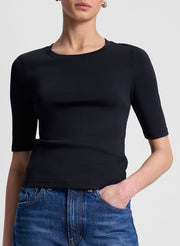 Person wearing a black short-sleeve top and blue jeans on a light gray background