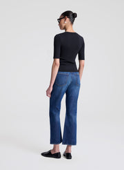 Woman wearing a black top and blue jeans on a white background