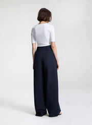 Person wearing a white top and navy wide-leg pants on a white background
