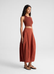 woman wearing maroon knit halter top and maroon midi skirt