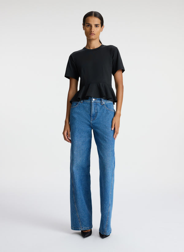 front view of woman wearing black peplum tee and blue jeans