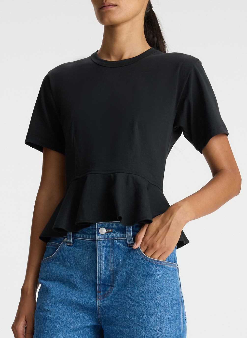detail view of woman wearing black peplum tee and blue jeans