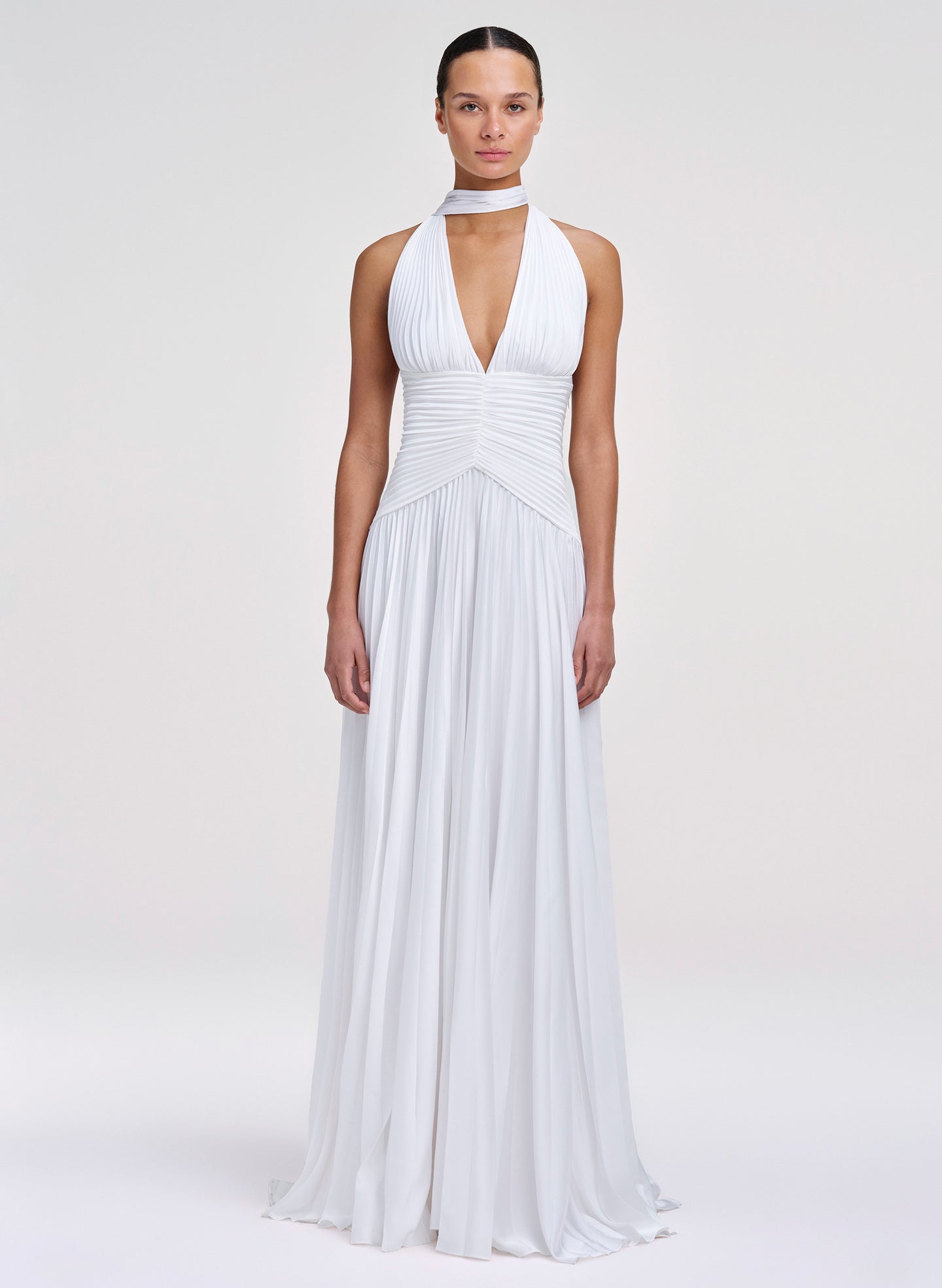 Woman wearing a white halter neck gown on a plain background