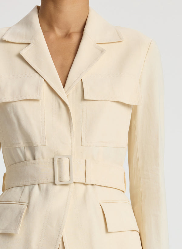 detail view of woman wearing beige belted jacket and beige wide leg pants