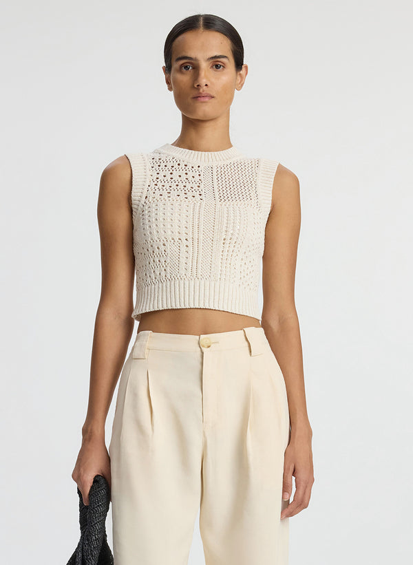 detail view of woman wearing cream sleeveless cropped crochet top and beige pants