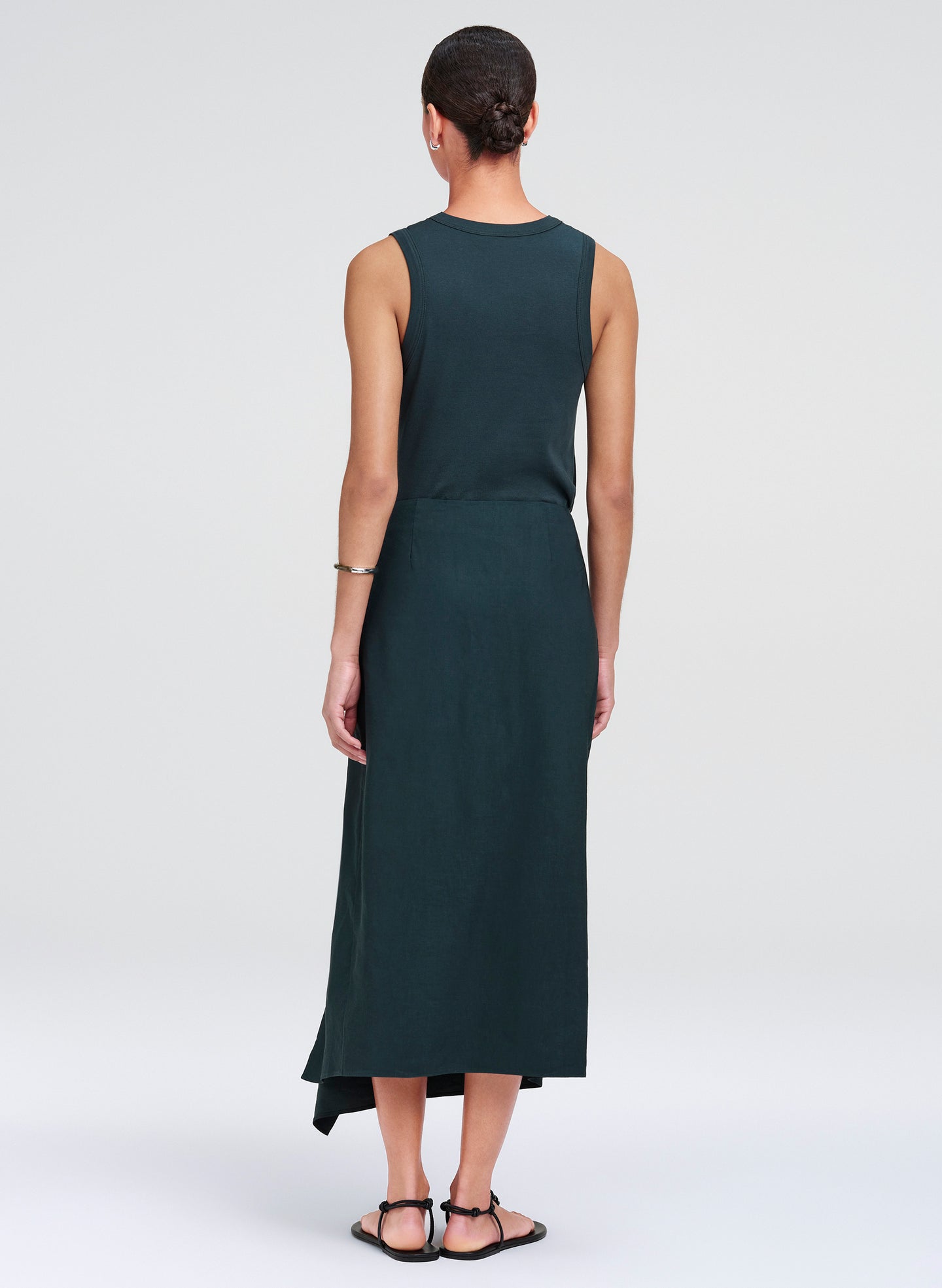 Woman wearing a dark green sleeveless top and skirt on a white background