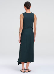 Woman wearing a dark green sleeveless top and skirt on a white background