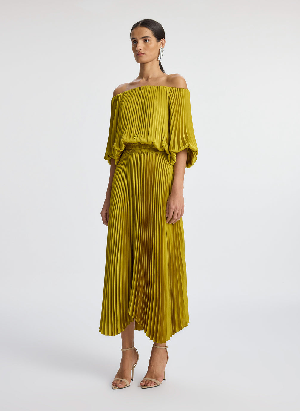 side view of woman wearing yellow pleated off shoulder dress