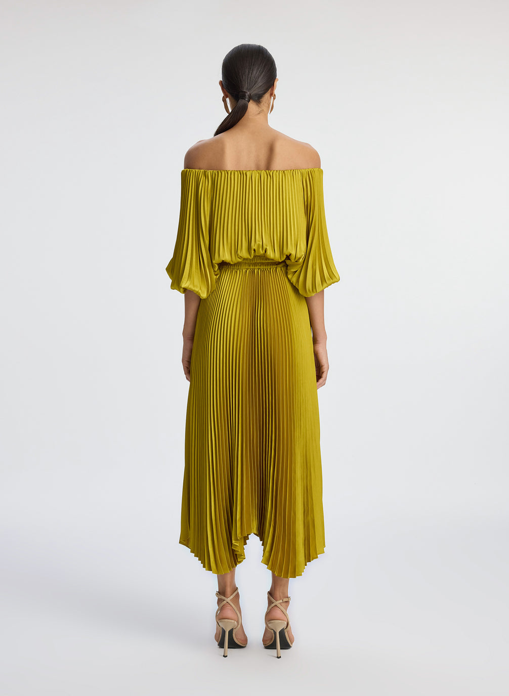 back view of woman wearing yellow pleated off shoulder dress