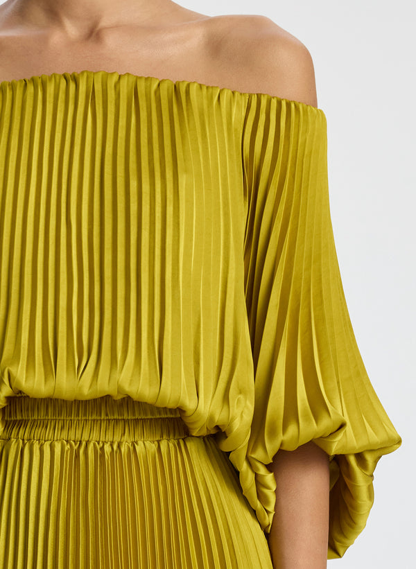 detail view of woman wearing yellow pleated off shoulder dress
