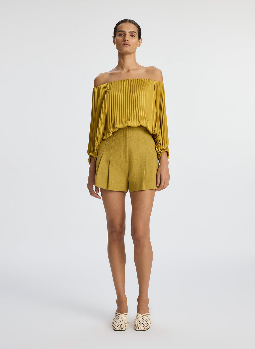 front view of woman wearing yellow pleated off shoulder top and yellow shorts