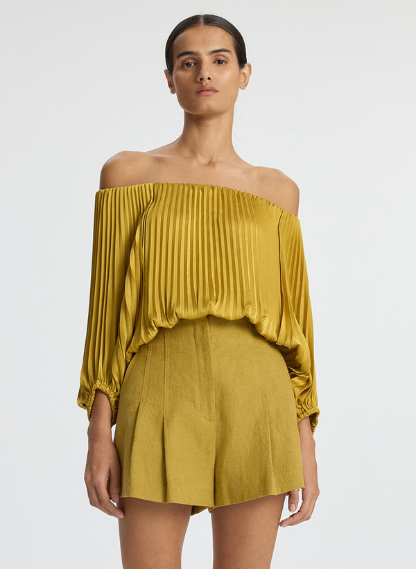 front view of woman wearing yellow pleated off shoulder top and yellow shorts
