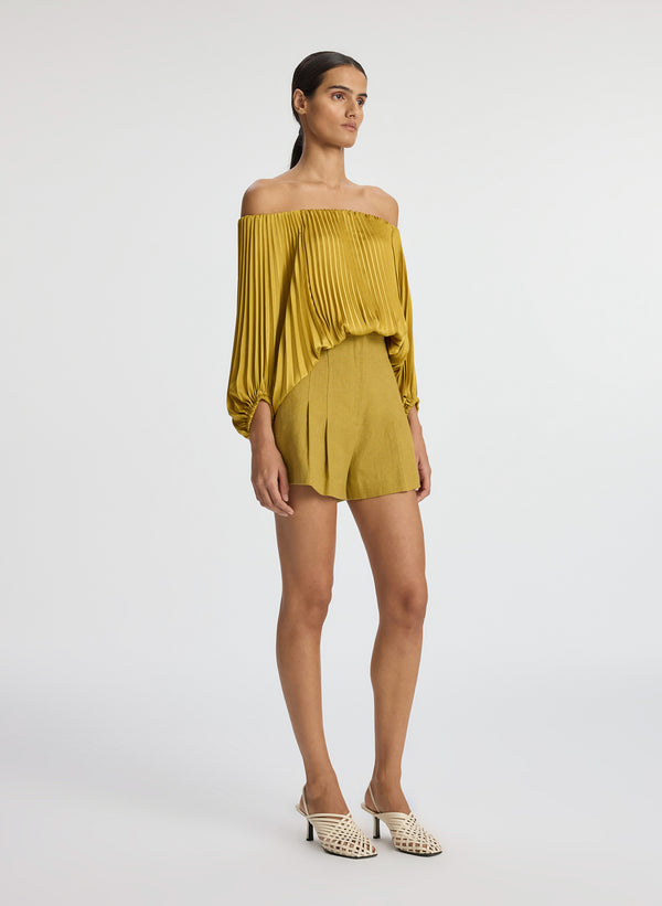 view of woman wearing yellow pleated off shoulder top and yellow shorts