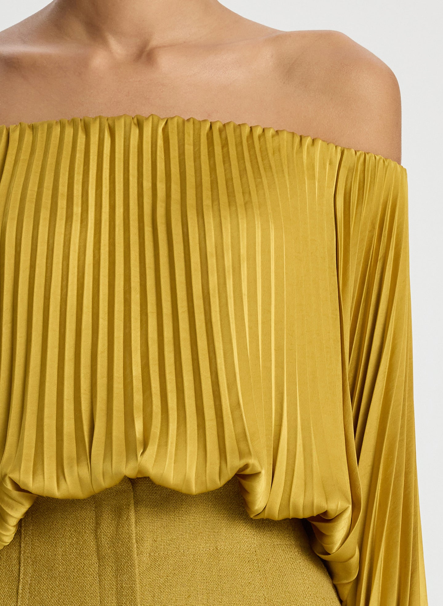 detail view of woman wearing yellow pleated off shoulder top and yellow shorts