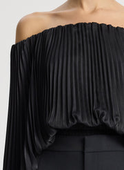 detail view of woman wearing black satin pleated off the shoulder top with black pants