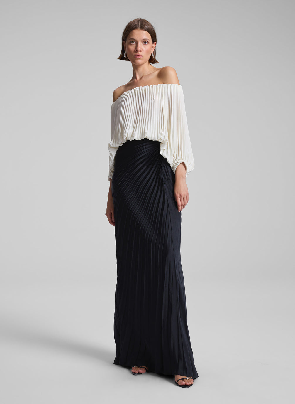 woman wearing white pleated top and black pleated maxi skirt