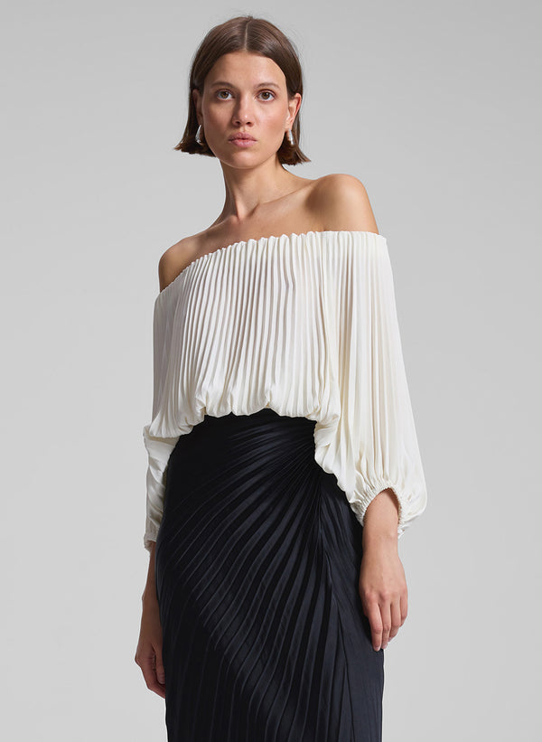 woman wearing white pleated op and black pleated skirt