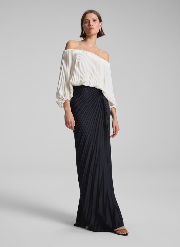 woman wearing white pleated top and black pleated maxi skirt