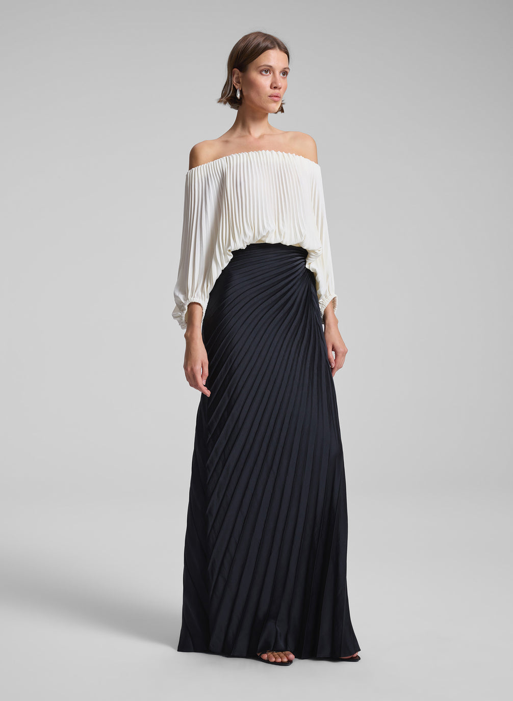 woman wearing white pleated op and black pleated skirt