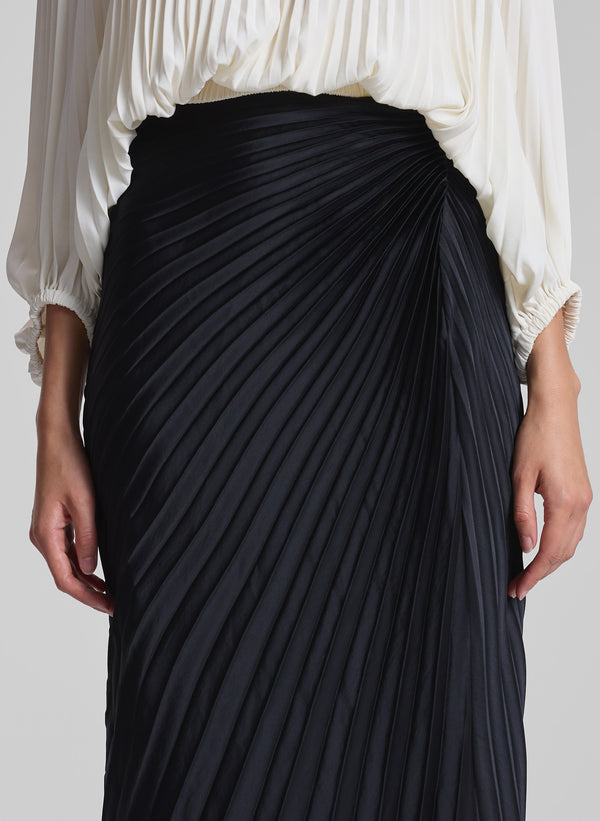 woman wearing white pleated top and black pleated maxi skirt