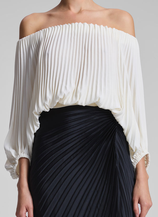 woman wearing white pleated op and black pleated skirt