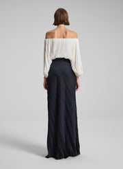 woman wearing white pleated top and black pleated maxi skirt