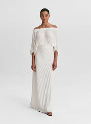 woman wearing pleated off shoulder top and pleated maxi skirt in white