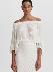 woman wearing white pleated top and matching set white pleated maxi skirt