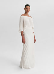 woman wearing pleated off shoulder top and pleated maxi skirt in white