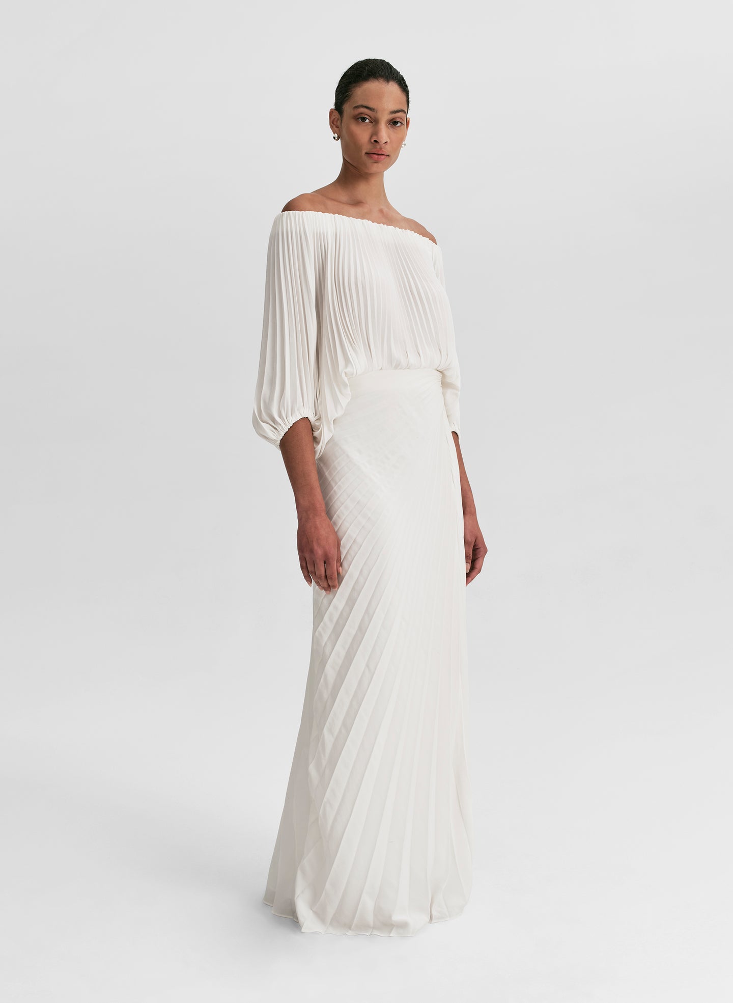 woman wearing white pleated top and matching set white pleated maxi skirt