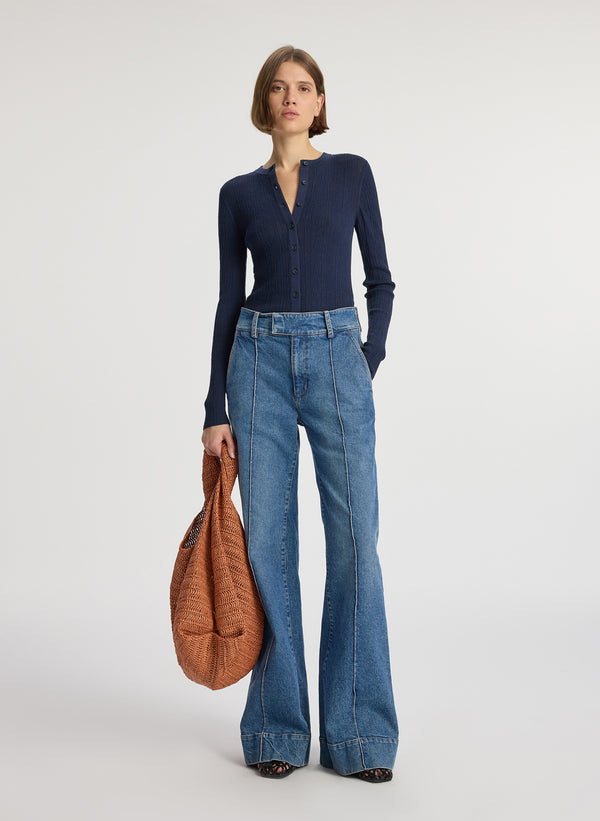 front view of woman wearing navy blue cardigan and medium blue wash wide leg denim jeans