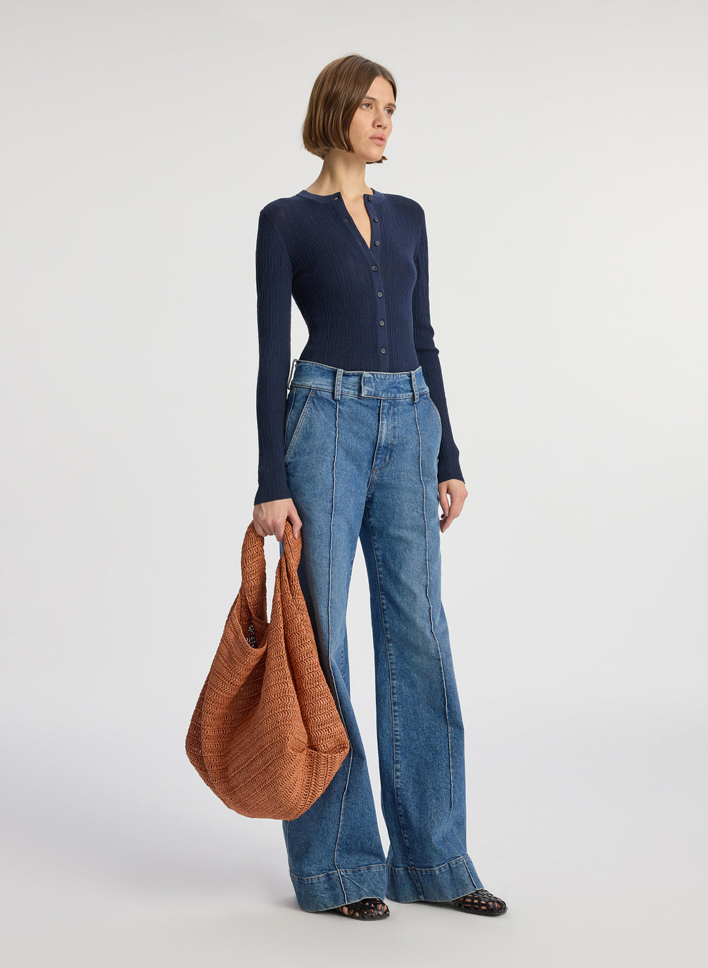 side view of woman wearing navy blue cardigan and medium blue wash wide leg denim jeans