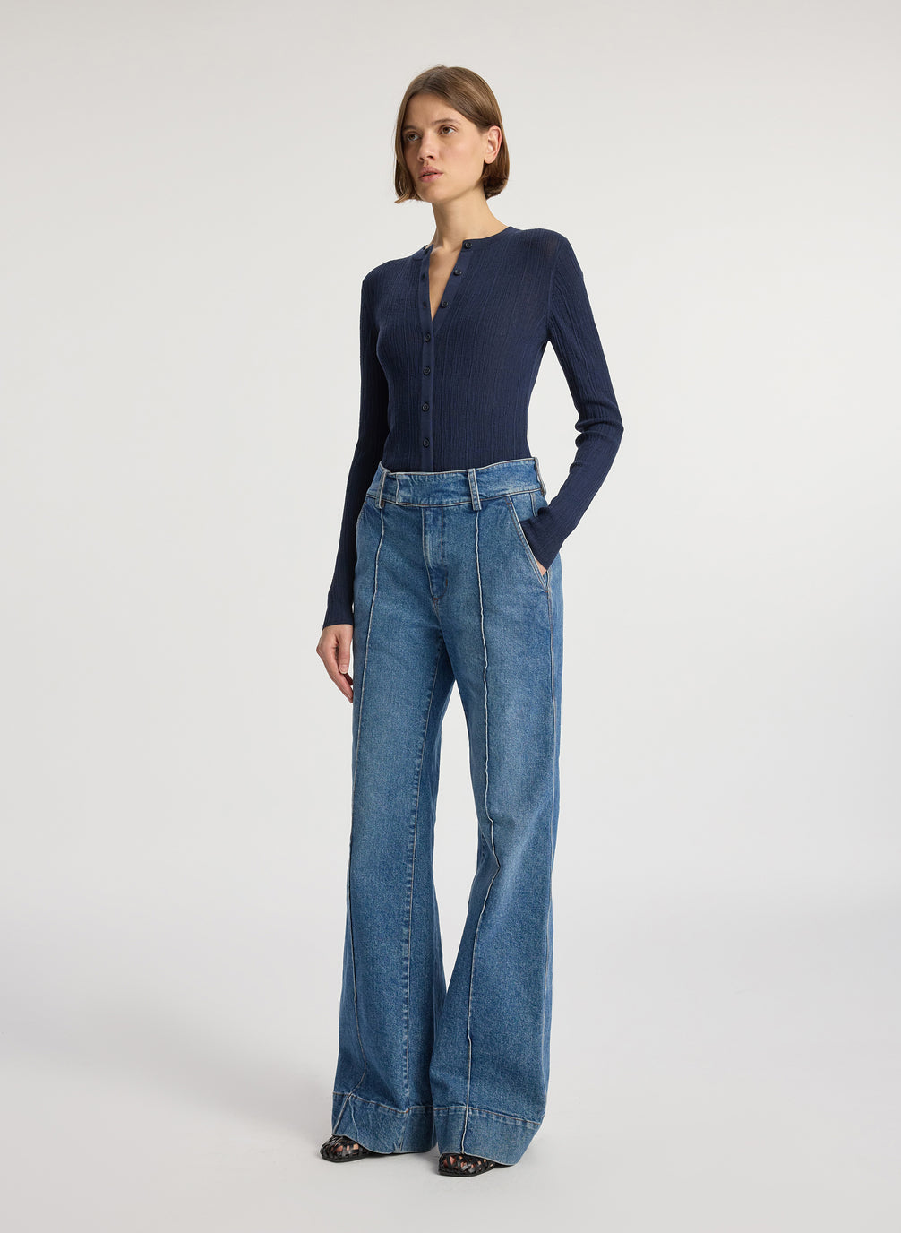 side view of woman wearing navy blue cardigan and medium blue wash wide leg denim jeans