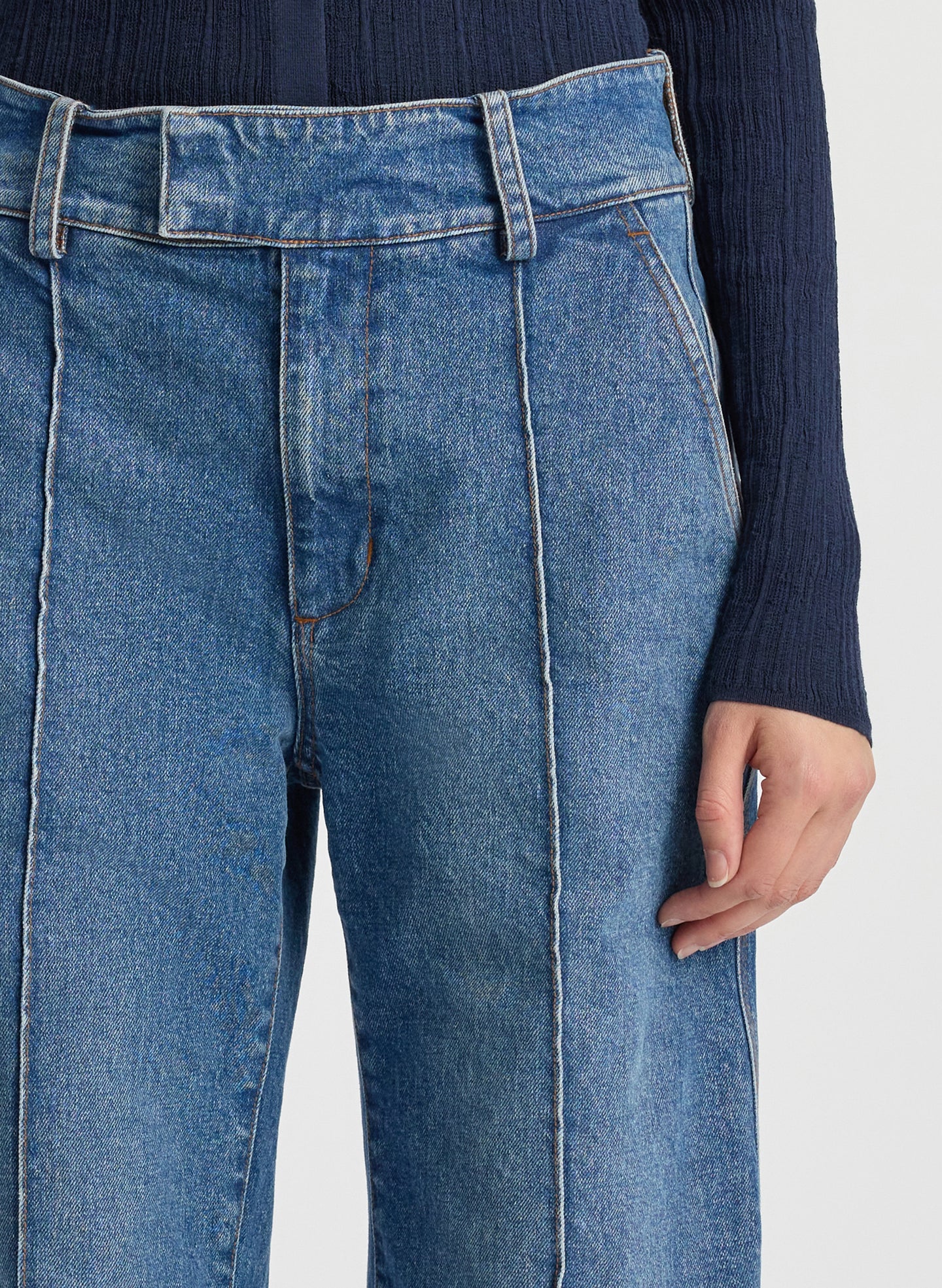 detail view of woman wearing navy blue cardigan and medium blue wash wide leg denim jeans
