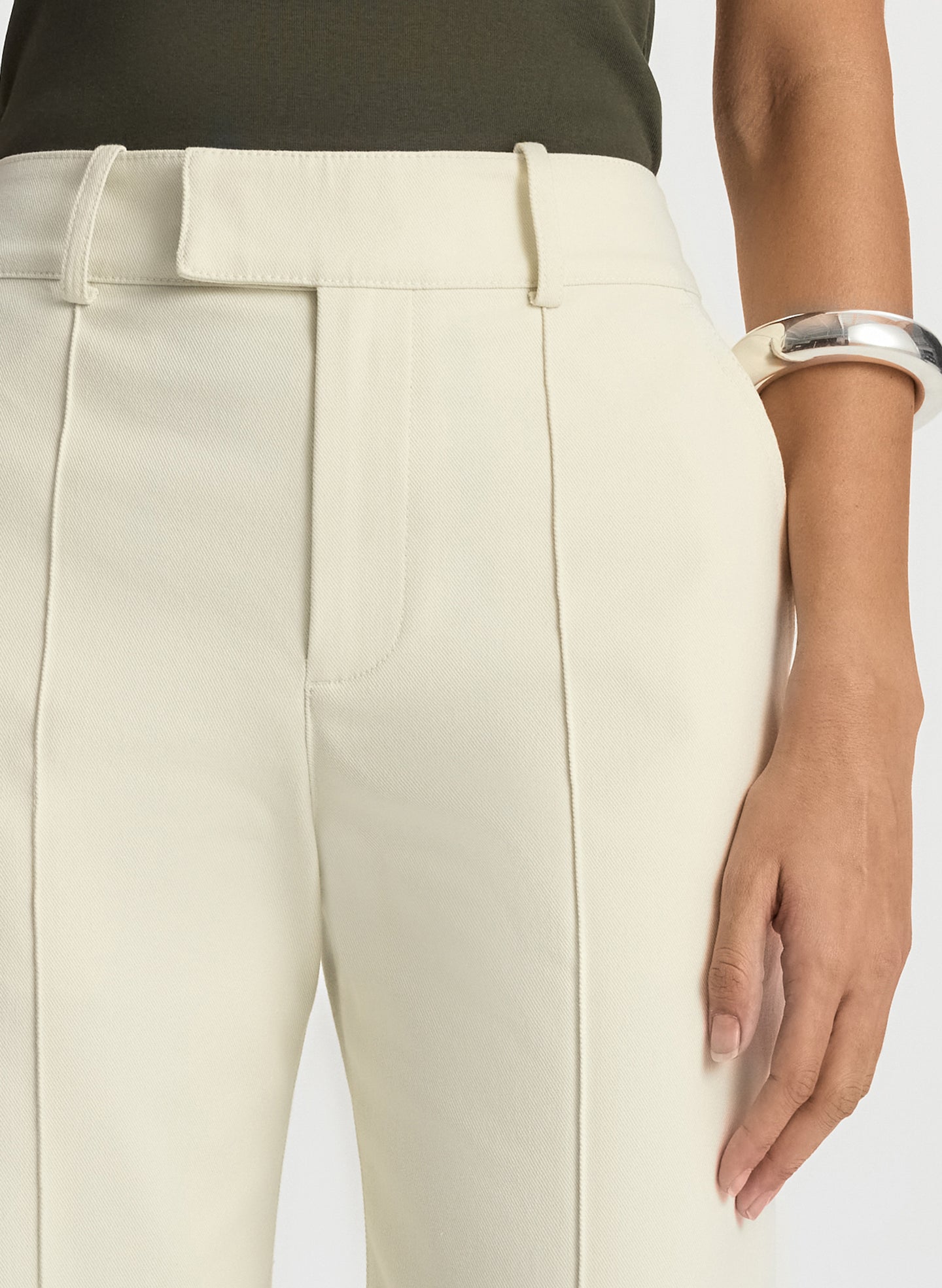 detail view of woman wearing olive green sleeveless top with cream wide leg pants