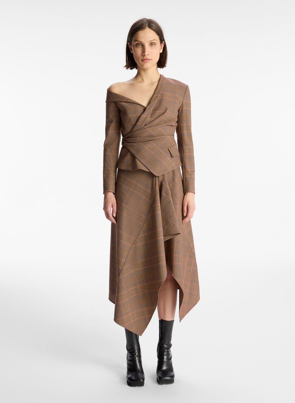 front view of woman wearing brown plaid asymmetric long sleeve top and matching brown plaid midi skirt