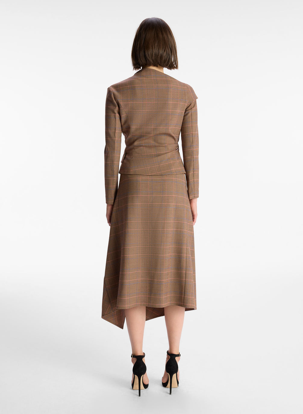 back view of woman wearing brown plaid asymmetric long sleeve top and matching brown plaid midi skirt