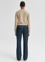 Person wearing a beige sweater and blue jeans on a white background