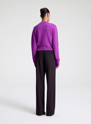 Person wearing a purple sweater and purple pants on a white background