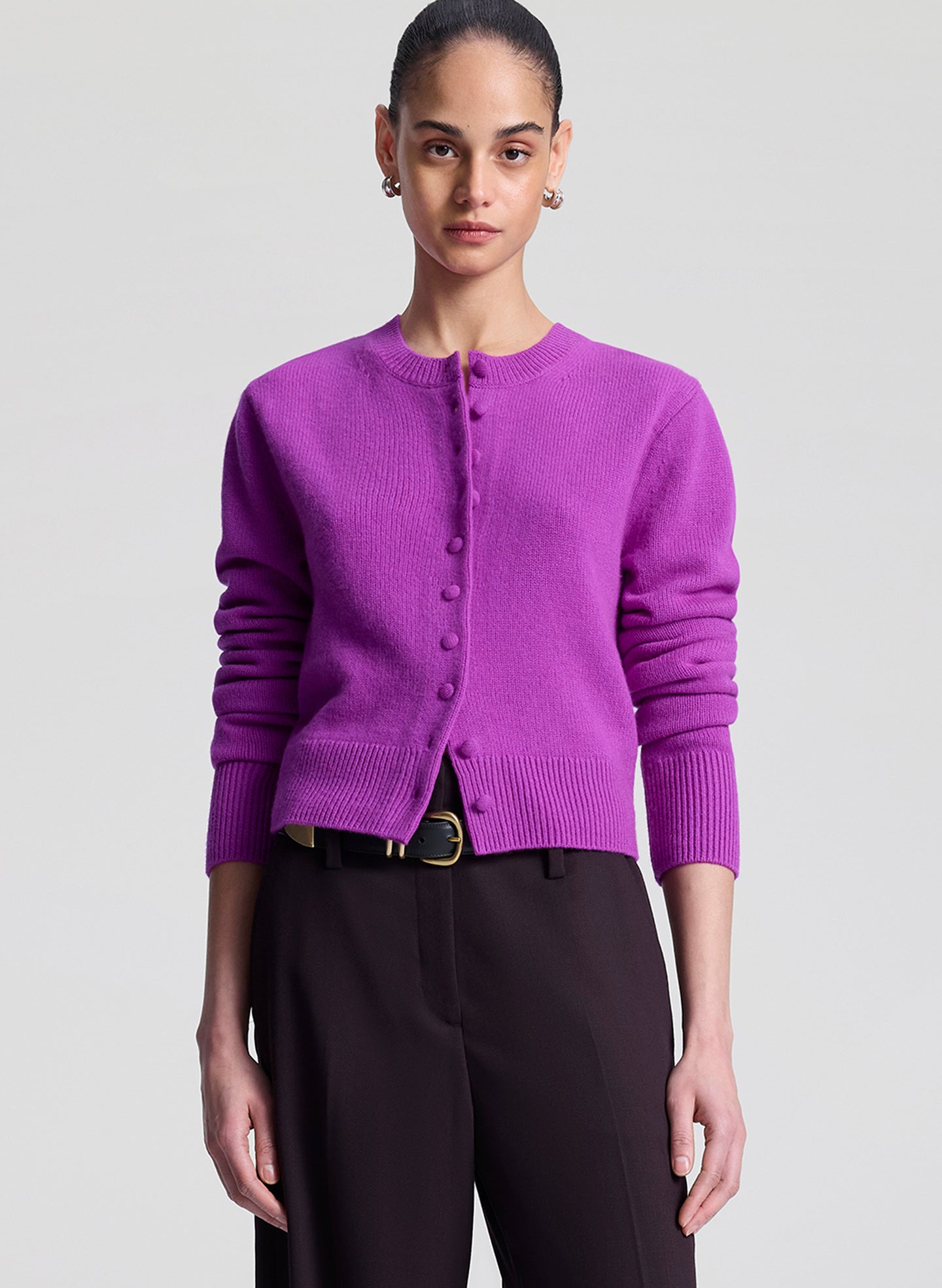 Person wearing a purple cardigan on a light gray background
