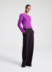 Person wearing a purple cardigan and purple pants on a white background