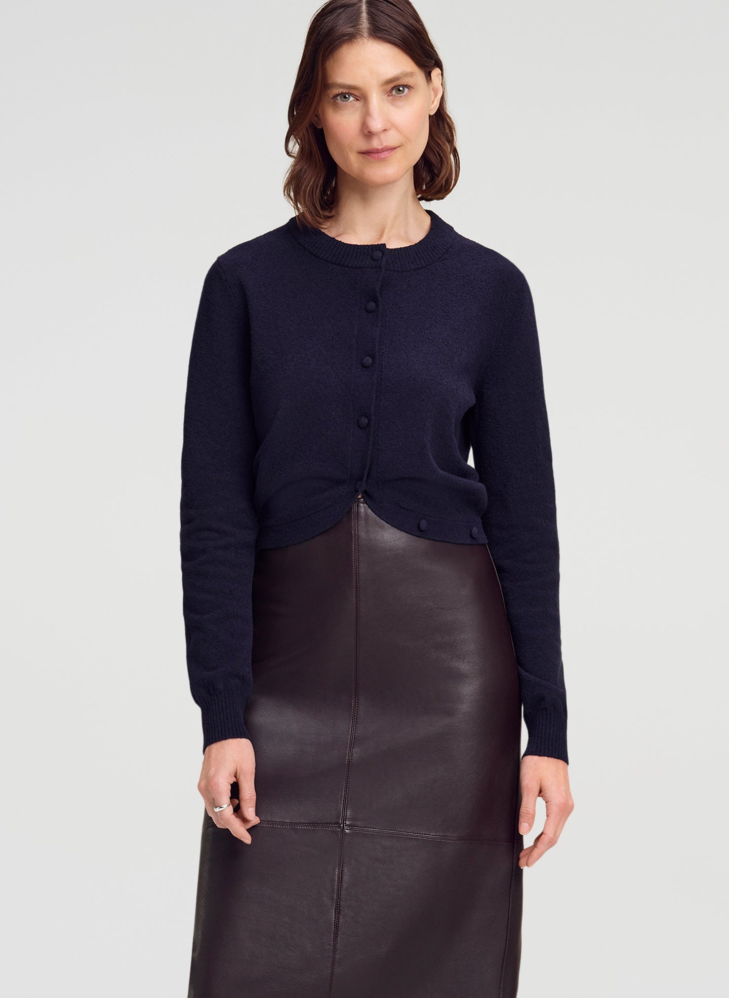 woman wearing navy blue cardigan and brown leather midi skirt