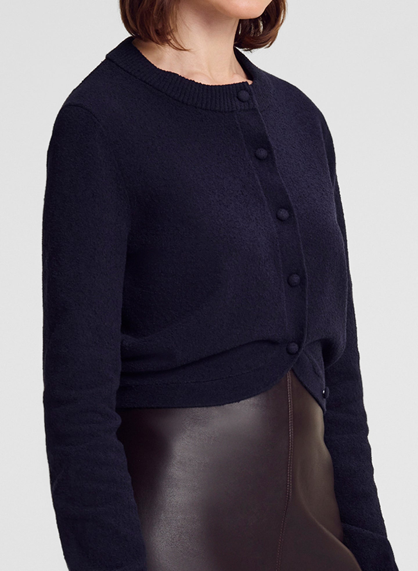 close up of woman wearing navy blue cardigan and brown leather midi skirt