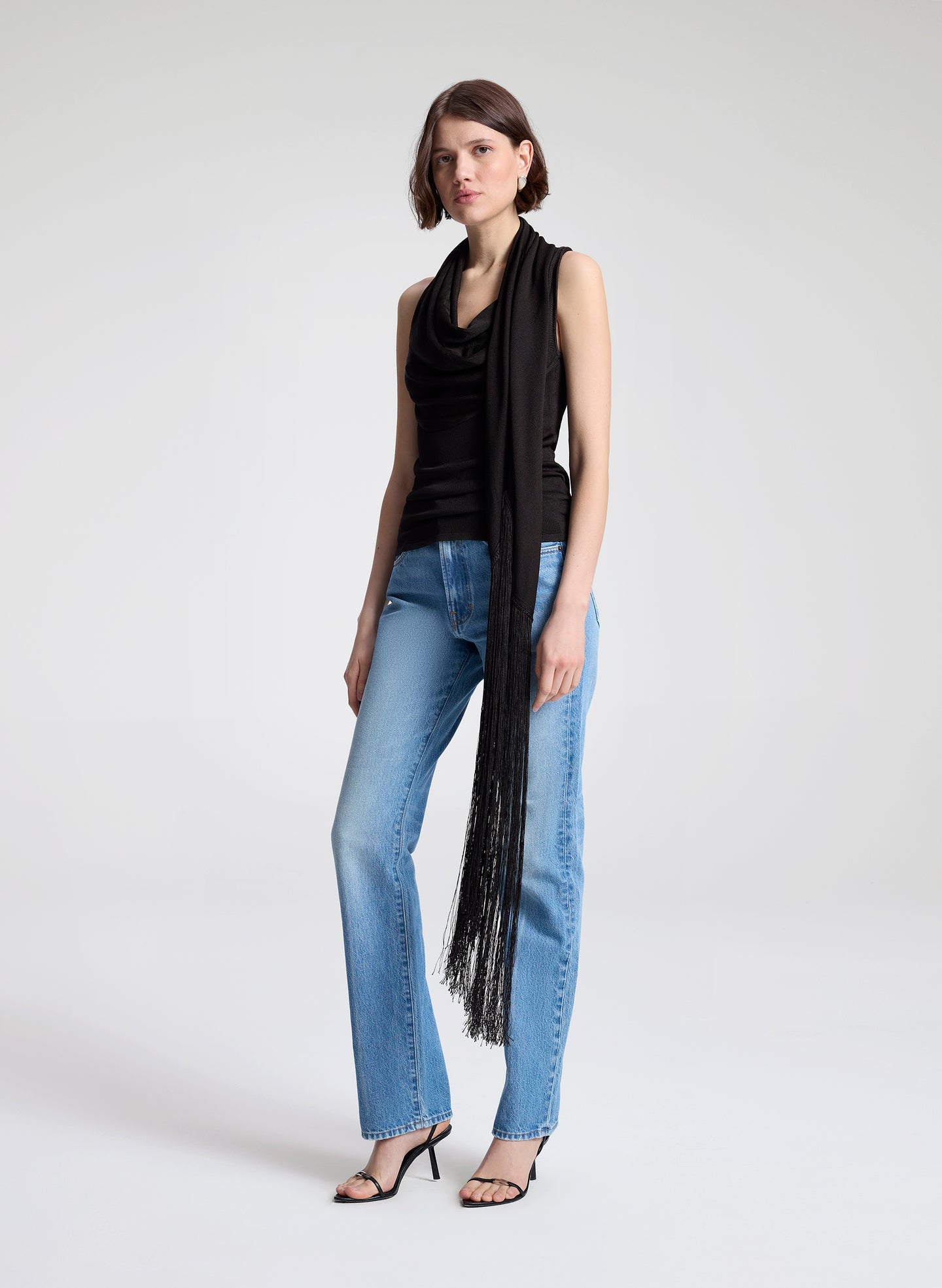 woman wearing dark brown draped top and  light blue denim straight leg jeans