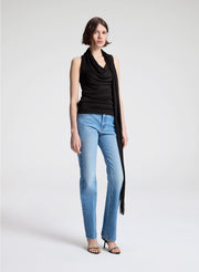 woman wearing dark brown draped top and  light blue denim straight leg jeans