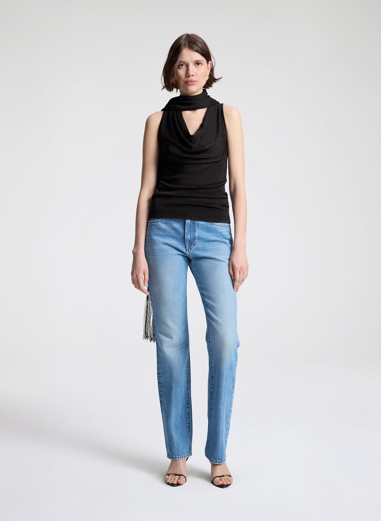 woman wearing dark brown draped top and  light blue denim straight leg jeans