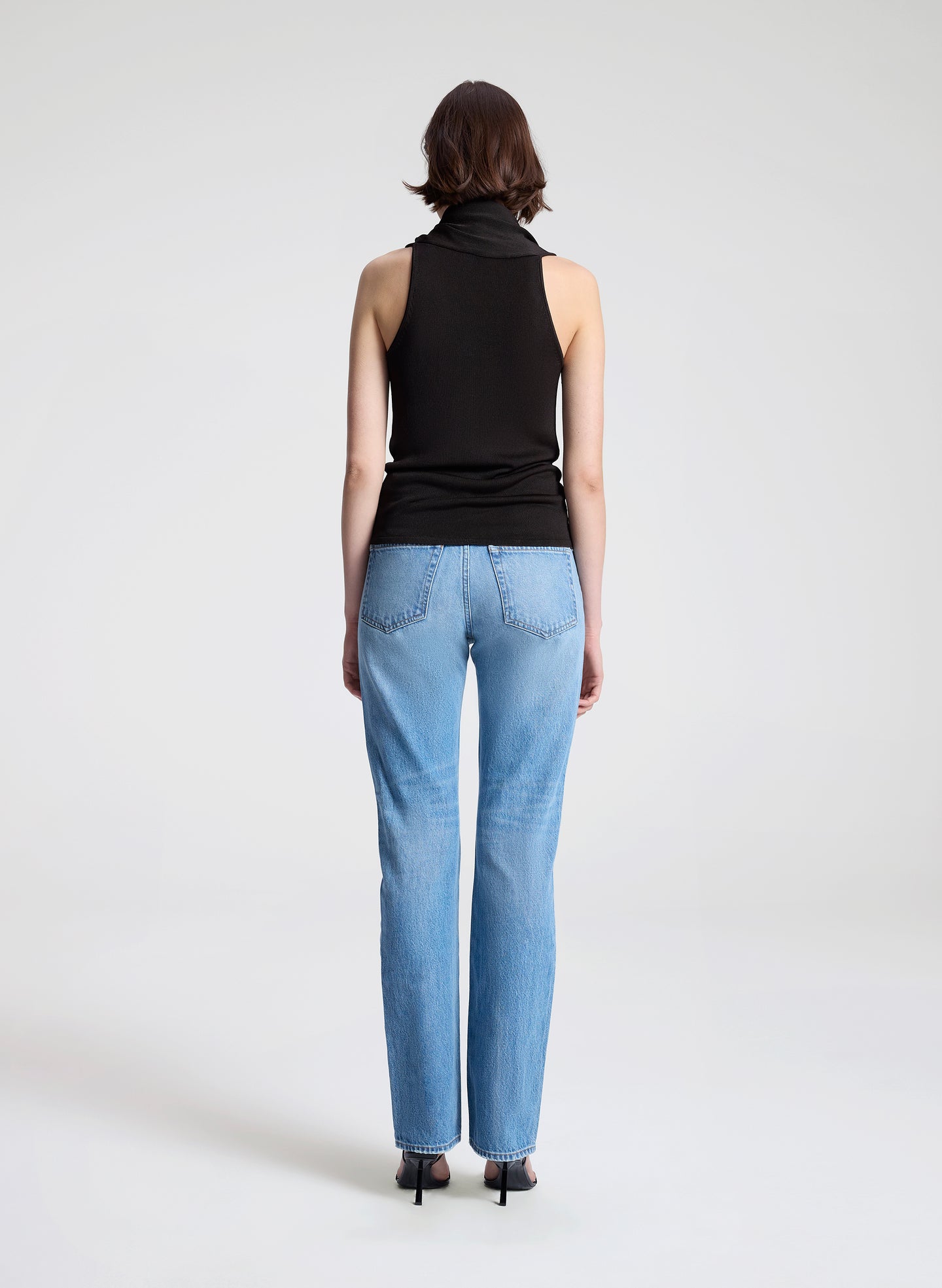 woman wearing dark brown draped top and  light blue denim straight leg jeans