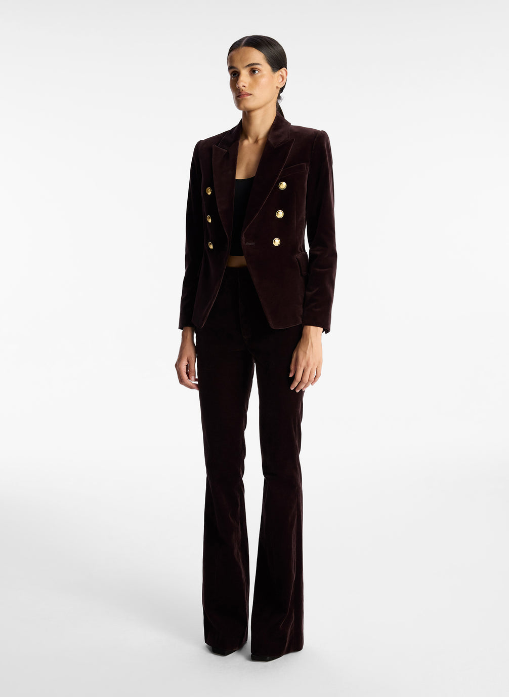 side view of woman wearing brown velvet jacket with gold buttons and brown velvet flared pants