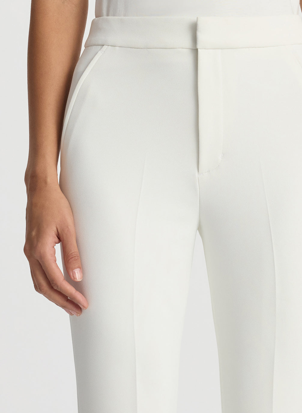 detail view of woman wearing white sleeveless shirt and white flared pants