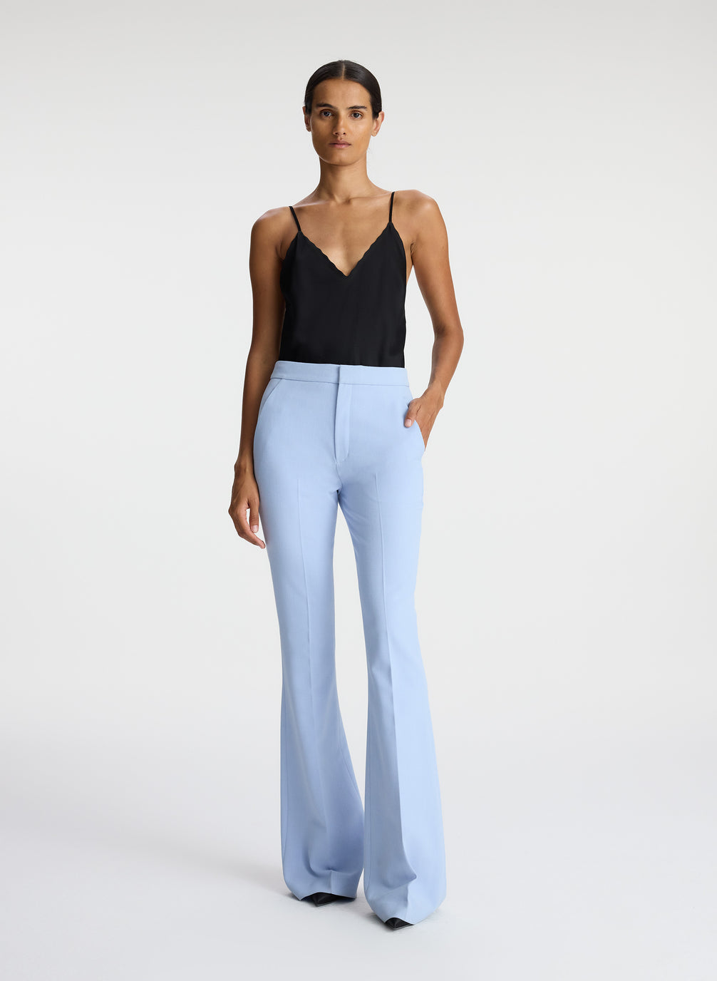 front view of woman wearing black satin camisole with light blue pants
